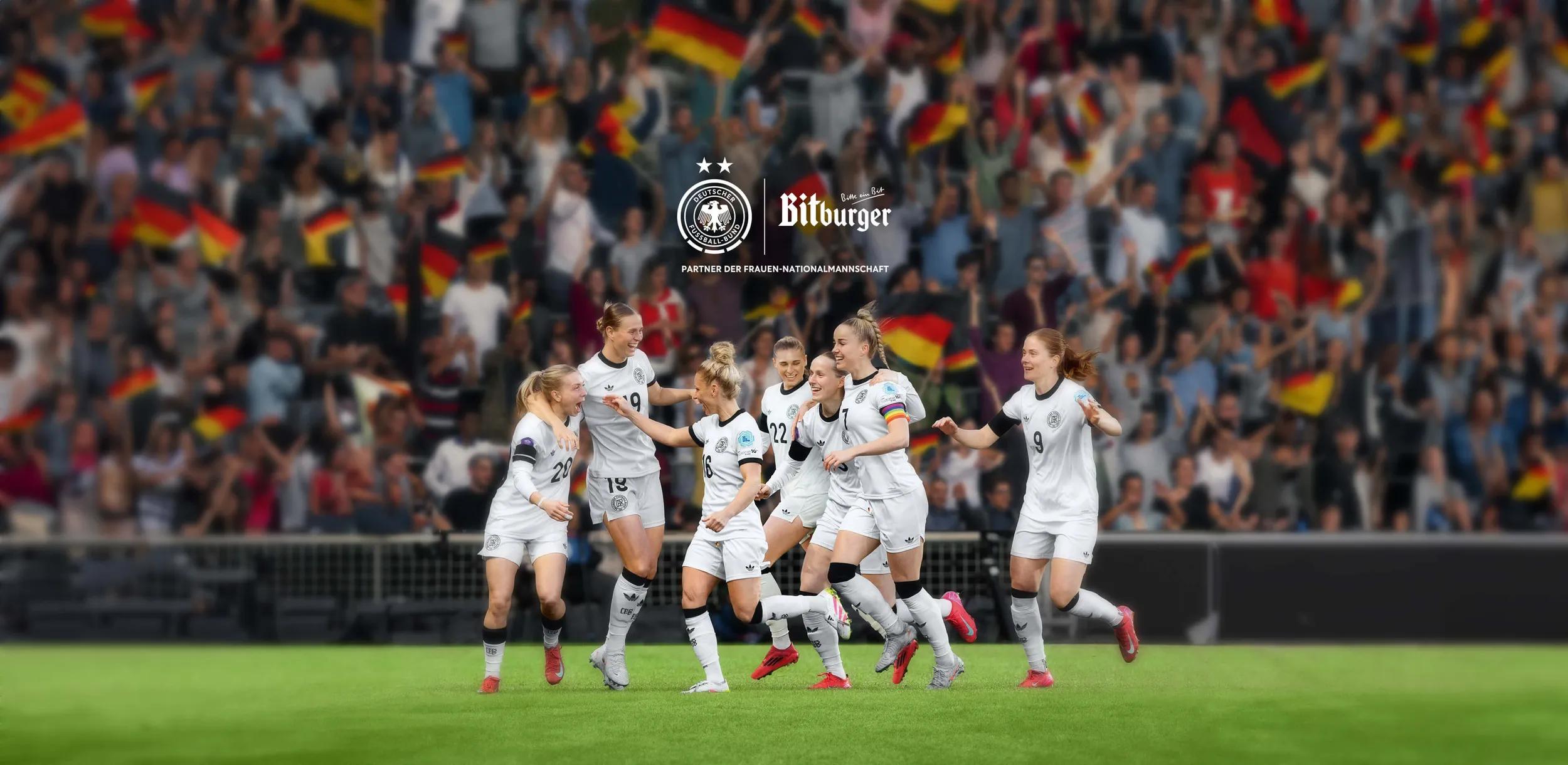Die DFB-Frauen-Fußball-Nationalmannschaft steht in einem Stadion und jubelt. Dabei laufen sie freudig auf dem Fußballfeld. Im Hintergrund sind die Fans auf der Tribühne.
