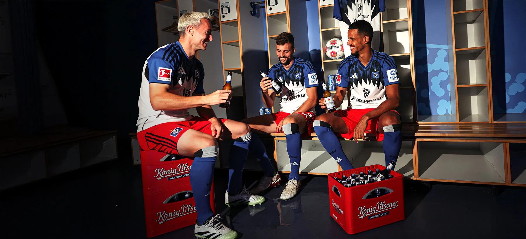 Drei HSV-Spieler sitzen in der Umkleidekabine und trinken gemeinsam König Pilsener Alkoholfrei.