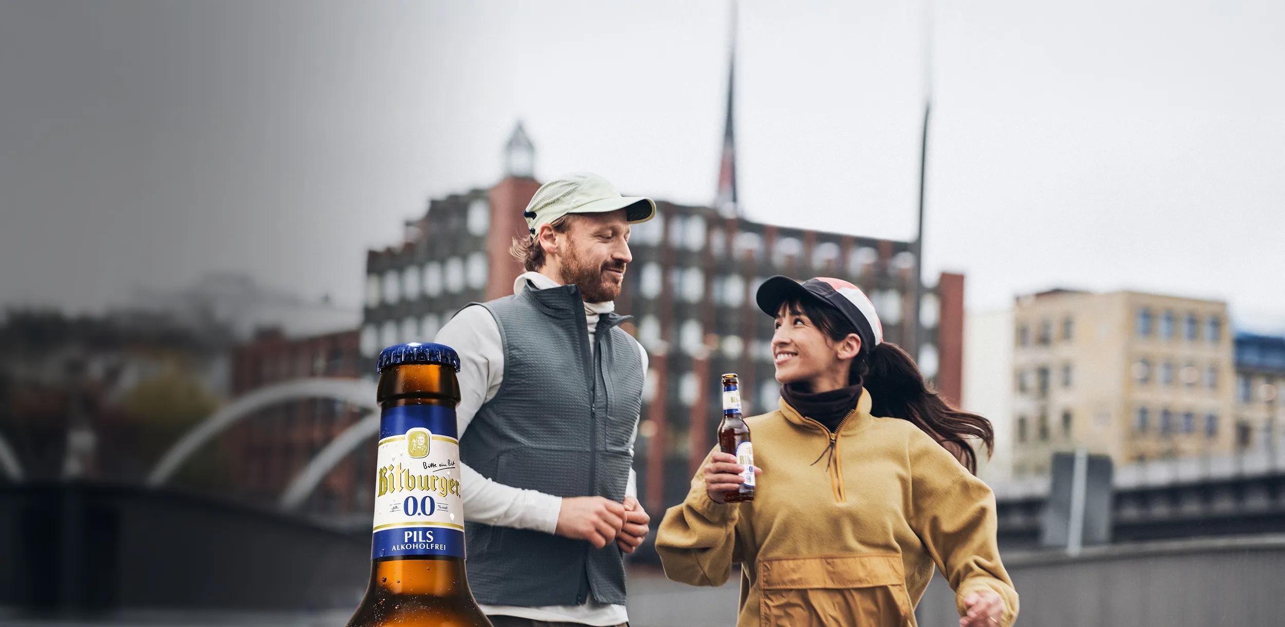 Zwei Läufer:innen sind im Training, eine der Personen hält eine Flasche hoch.