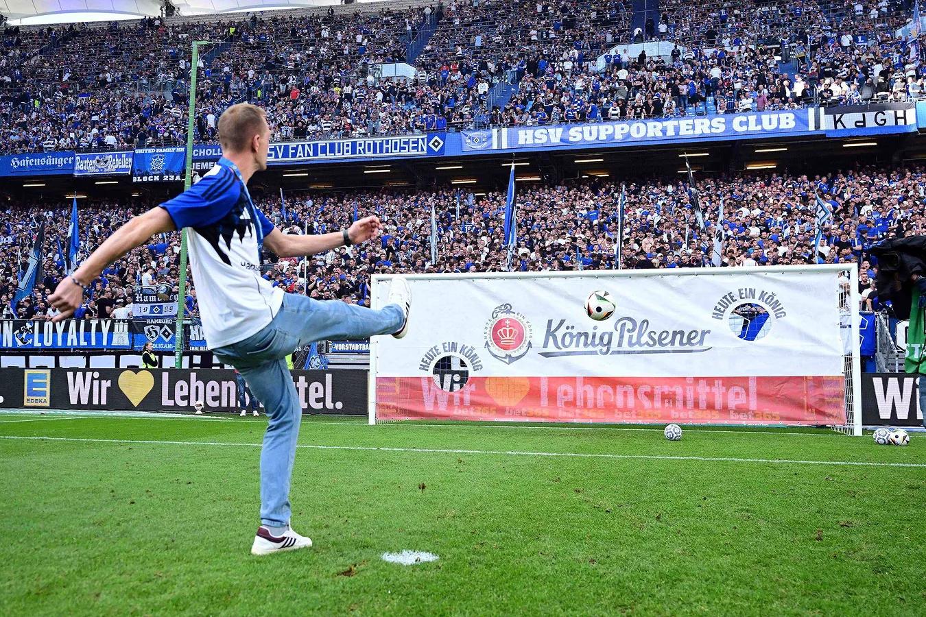 Ein Fan schießt bei vollem Stadion auf eine Torwand.