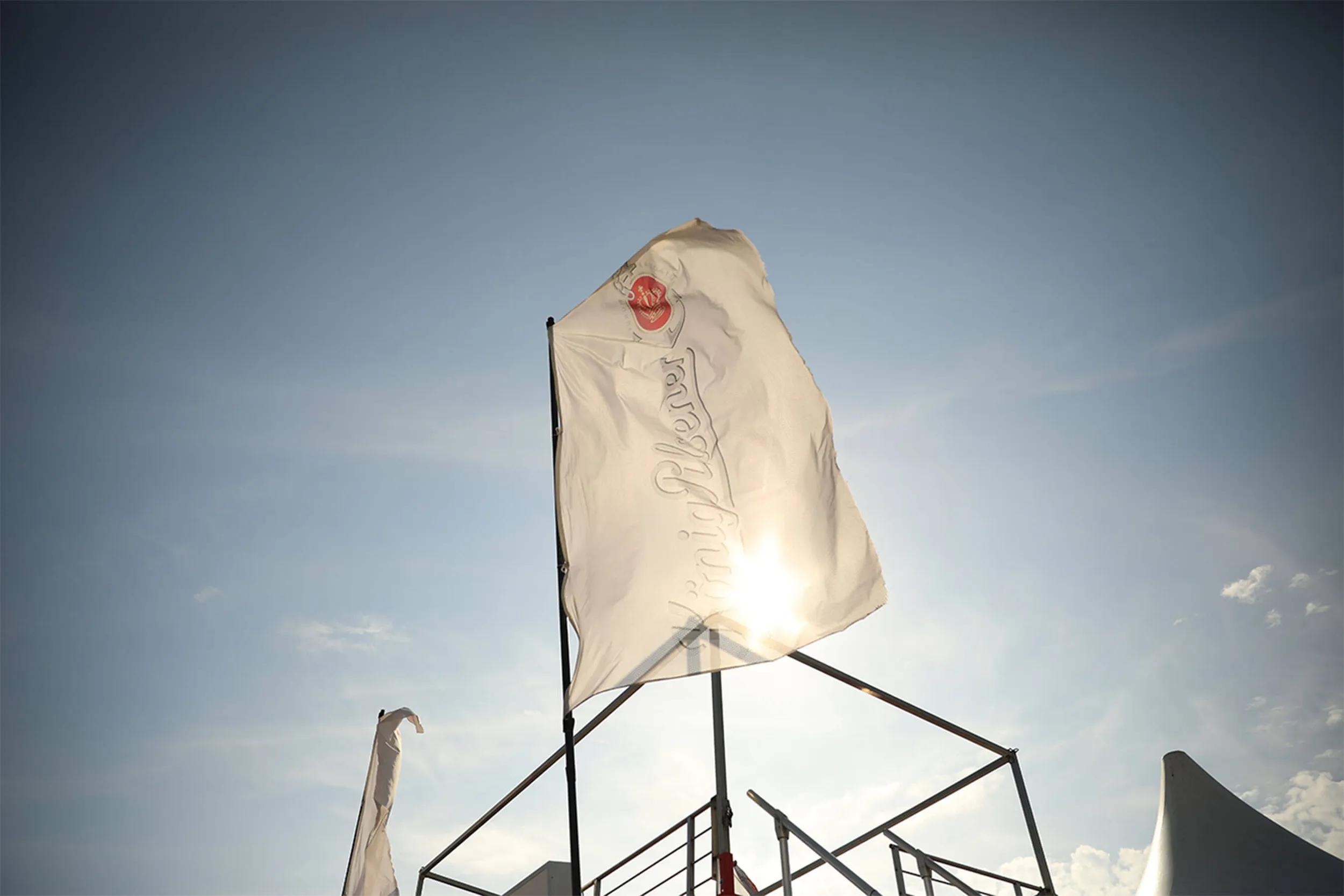 Weiße König Pilsener Flagge im Wind vor Sonne.