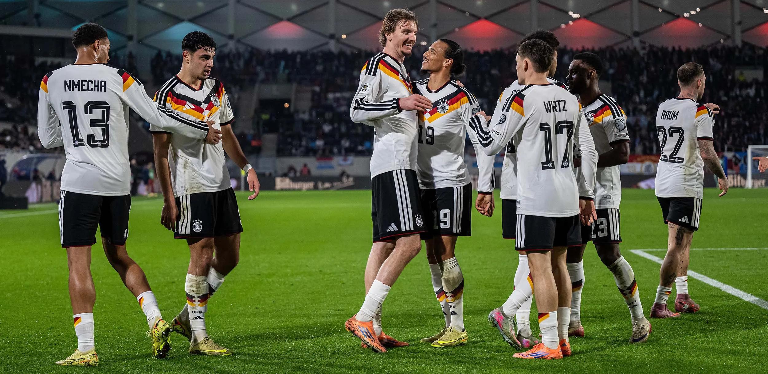 Das Männer DfB-Team steht auf einem Fußballfeld und jubelt.