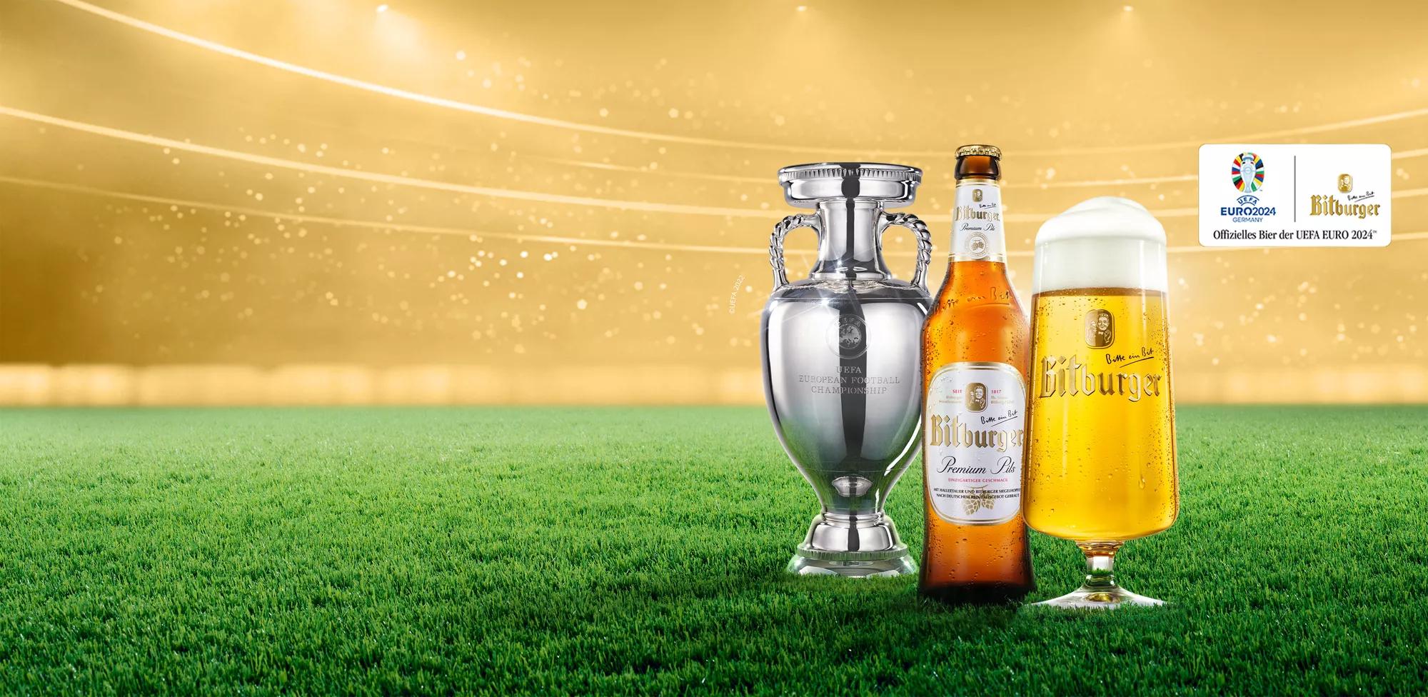 Teaser UEFA Euro Pokal, Flasche und gefülltes Bierglas auf Rasen vor goldenem Hintergrund