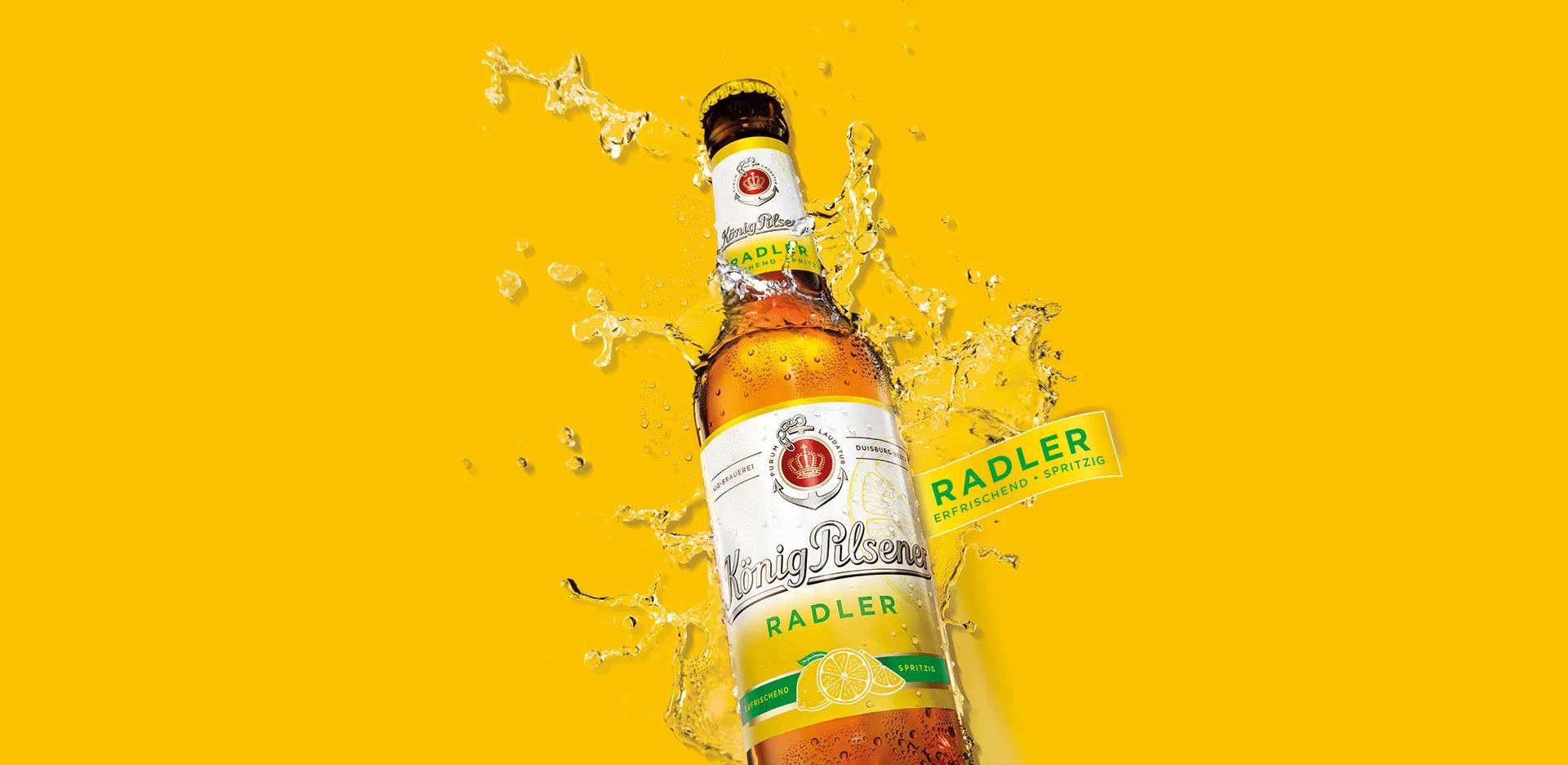 Flasche König Pilsener Radler mit erfrischenden Wassertropfen und Zitronenillustration auf knallgelbem Hintergrund – spritzig, frisch und sommerlich inszeniert.