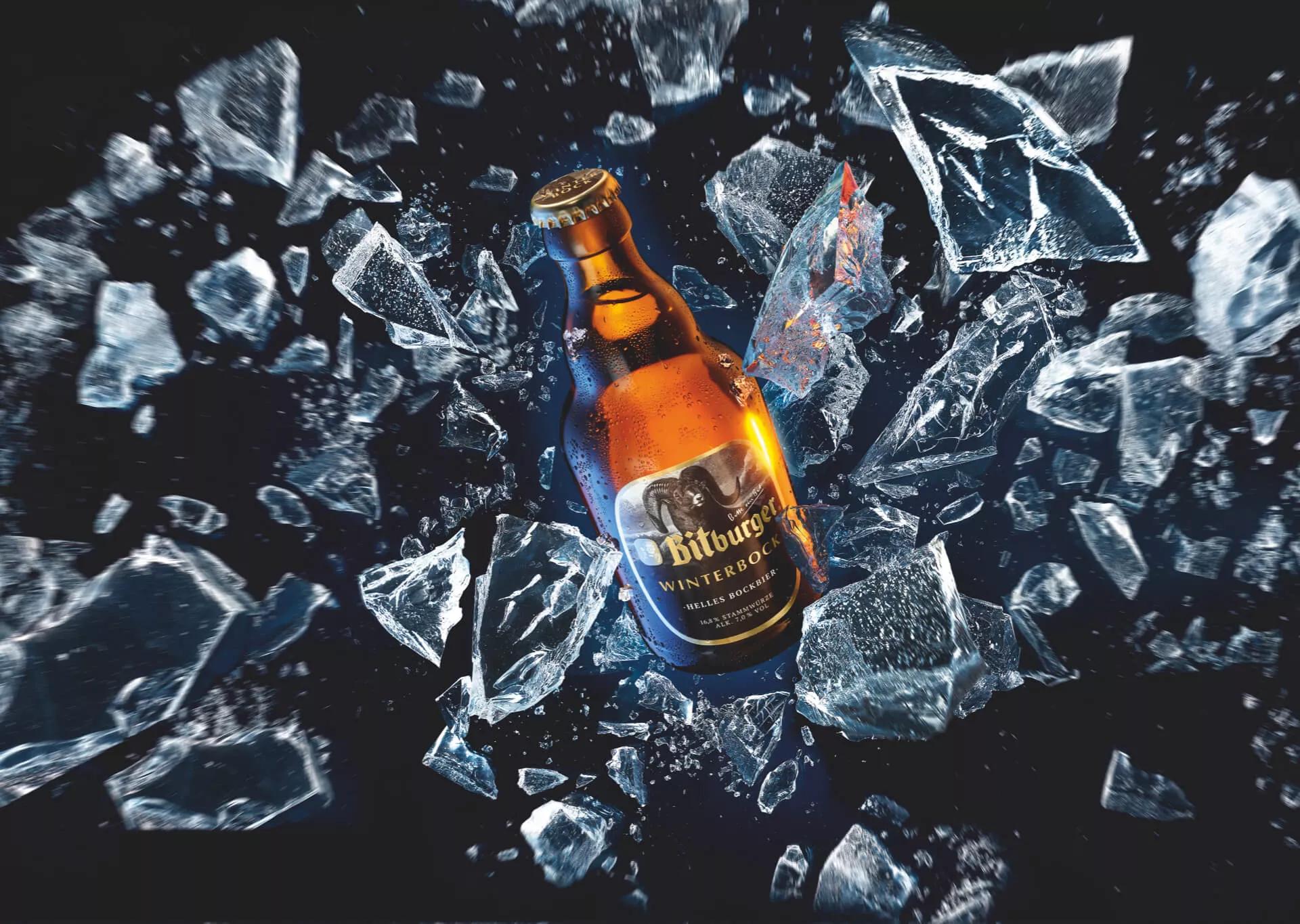 Flasche im Stubbi Format mit Winterbock Etikett vor dunkelblauem Hintergrund und zerschmettertem klaren Eis