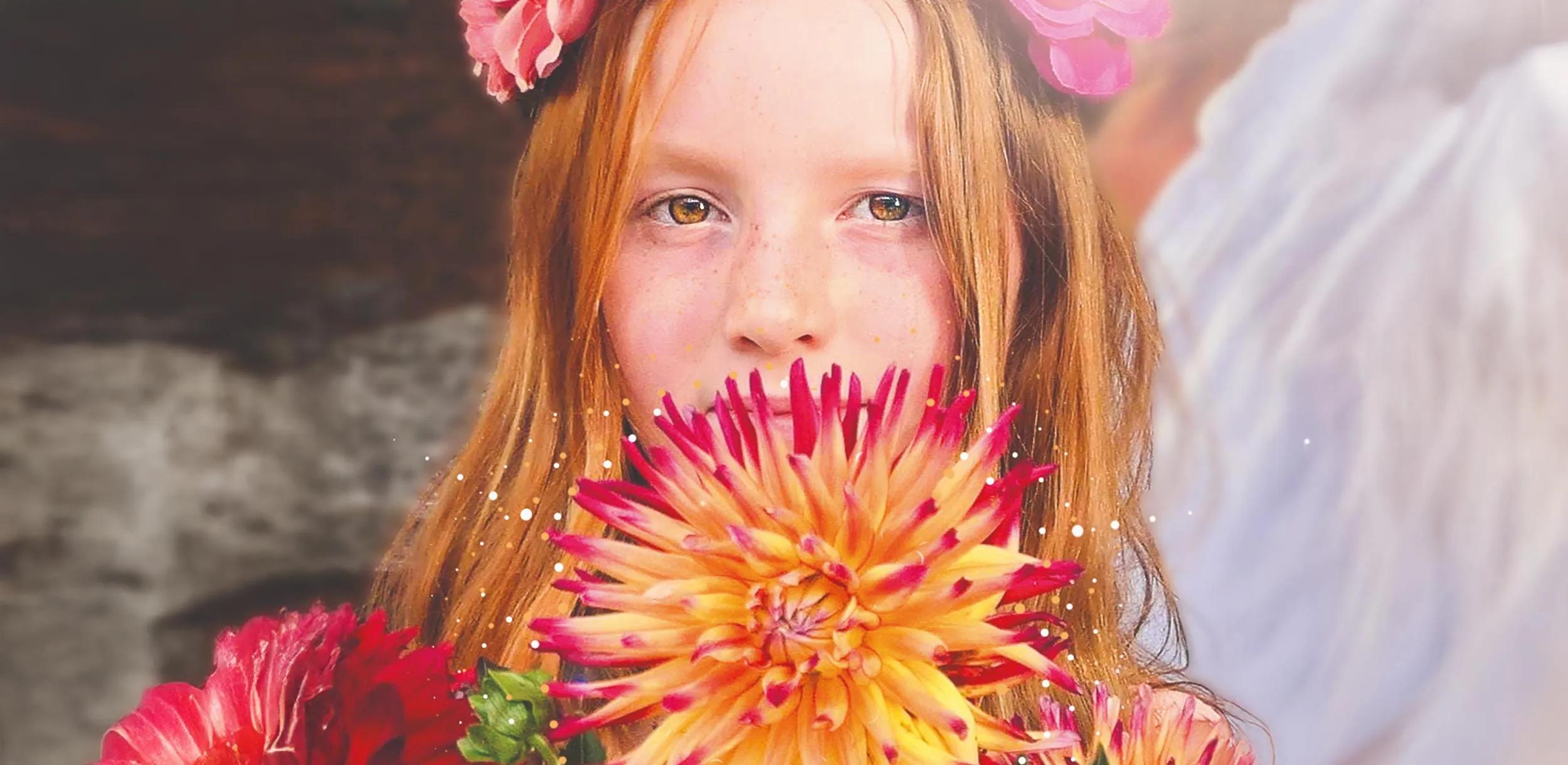 Mädchen mit Blumenkrone hält einen Blumenstrauß vor ihrem Gesicht.