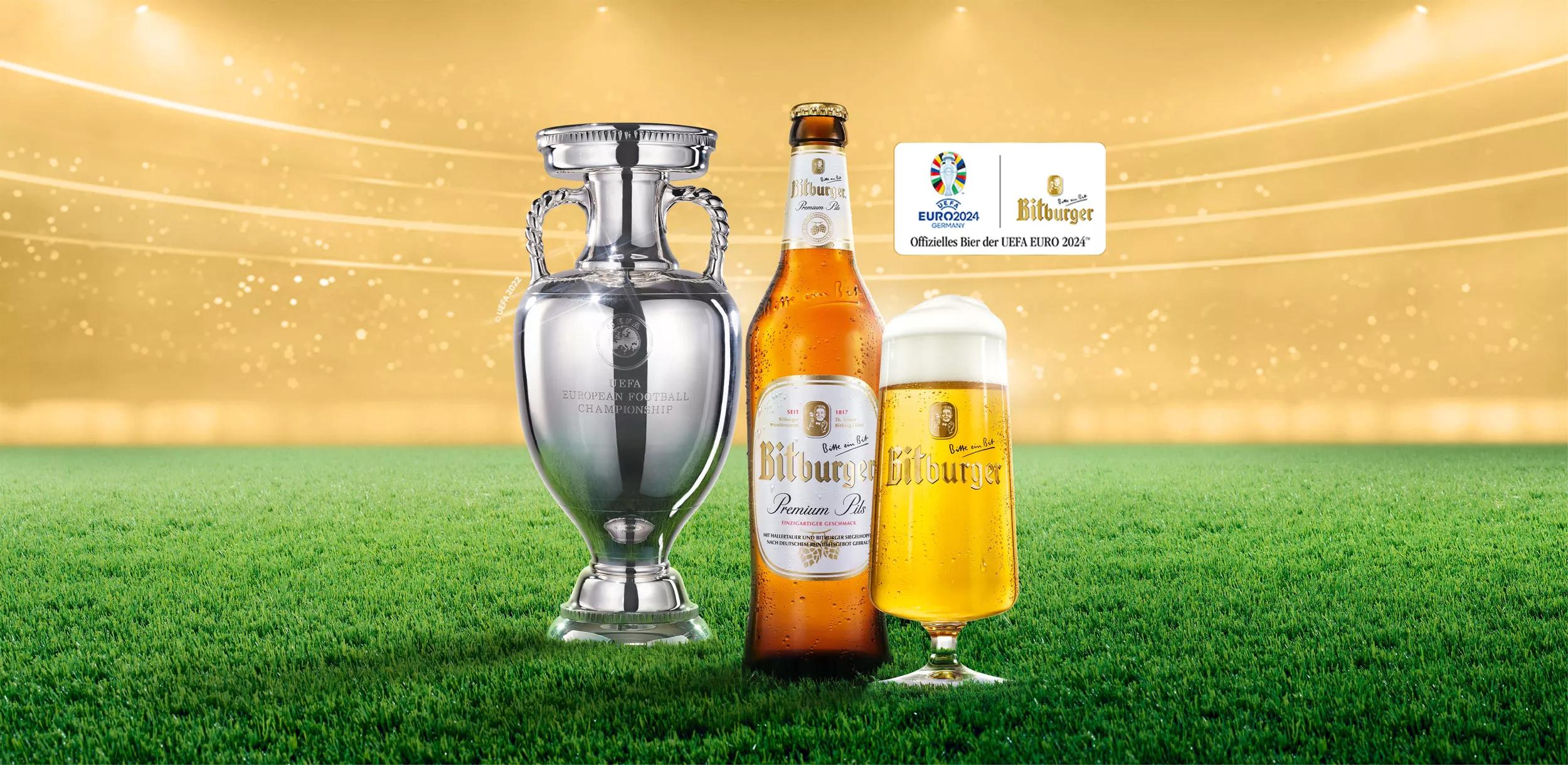 Teaser mobil optimiert, links UEFA EURO 2024tm Pokal, Mitte Bitburger Premium Pils Bierflasche, rechts Bitburger Bierglas auf Rasen mit goldenem Hintergrund, der funkelt