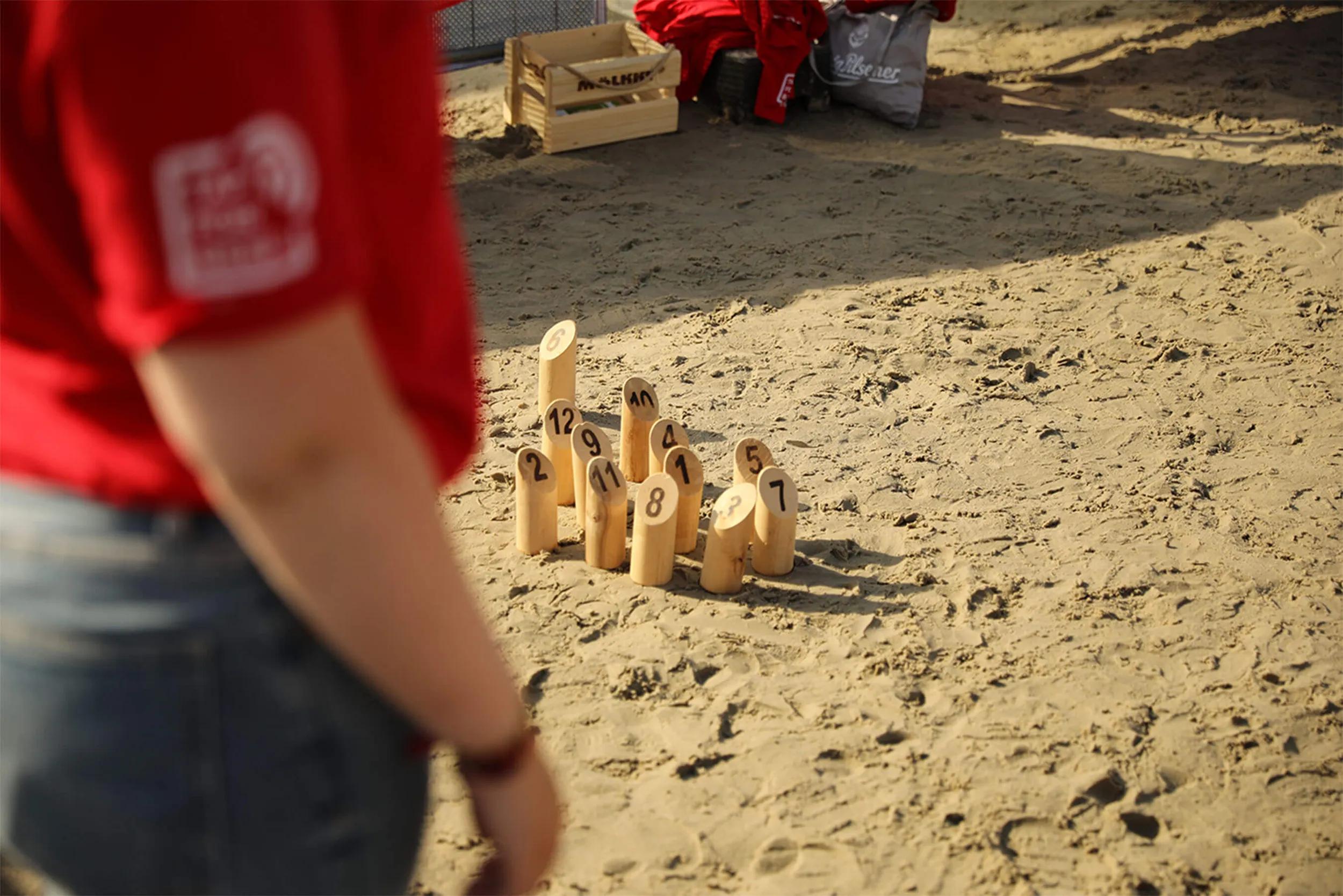 Holzstäbe vom Spiel Mölkky im Sand.